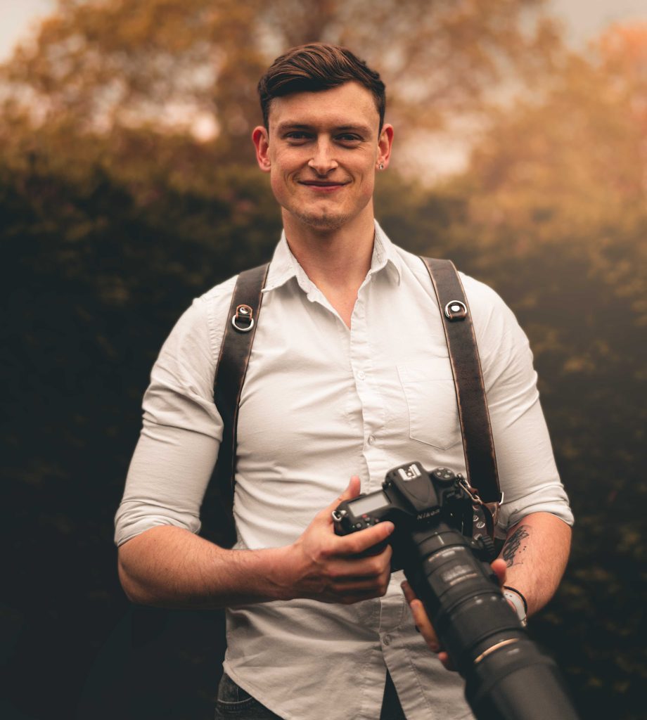 Nathan Warren, wedding photographer, holding his camera in warm autumn light