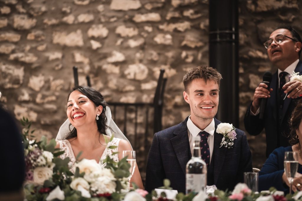 Bride and groom laughing at the top table during the speeches