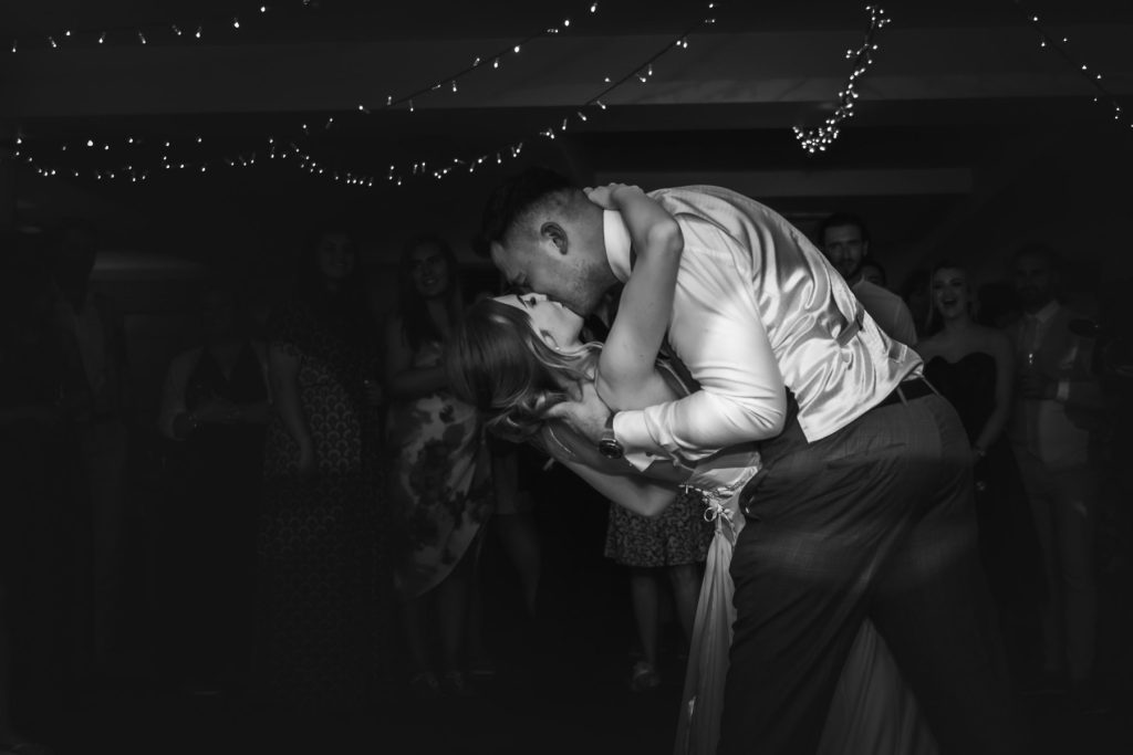 Black and white photo of the groom dipping the bride on a crowded dance floor