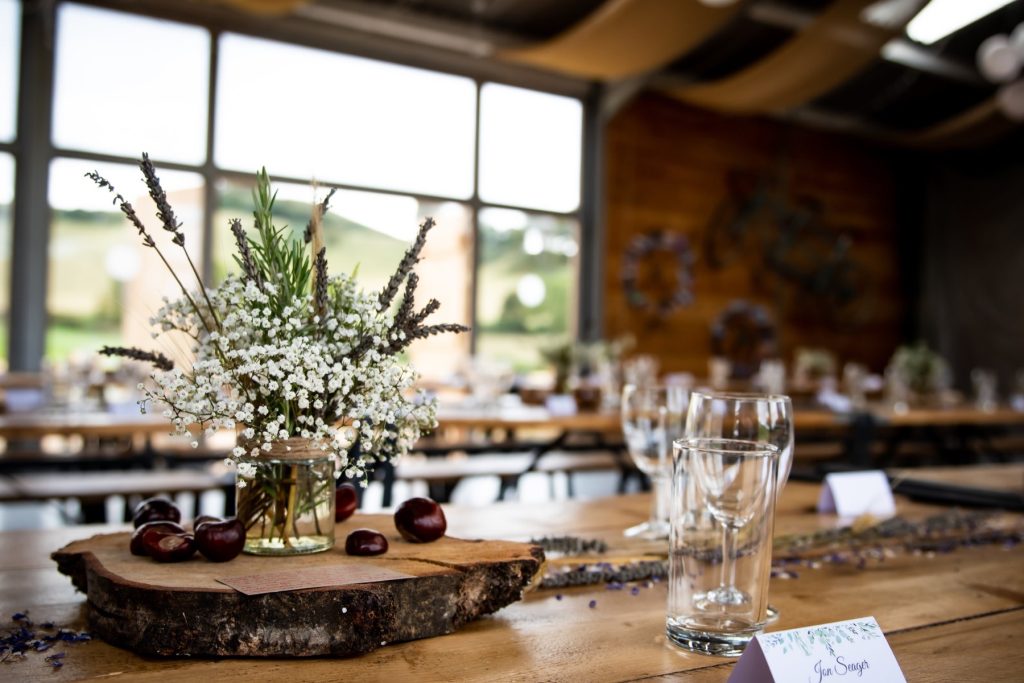 Gypsophila centrepiece on a wooden slice at a rustic reception table beside tall windows