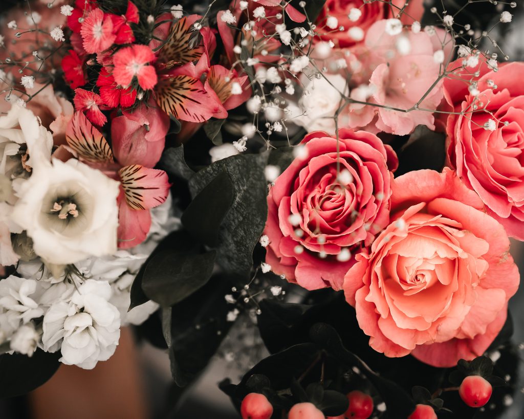 Close-up of a wedding bouquet of coral and pink roses with white carnations and gypsophila