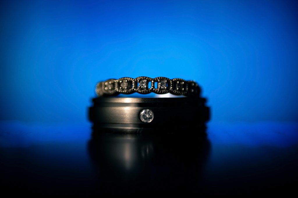 Wedding rings stacked on a reflective surface against a deep blue background